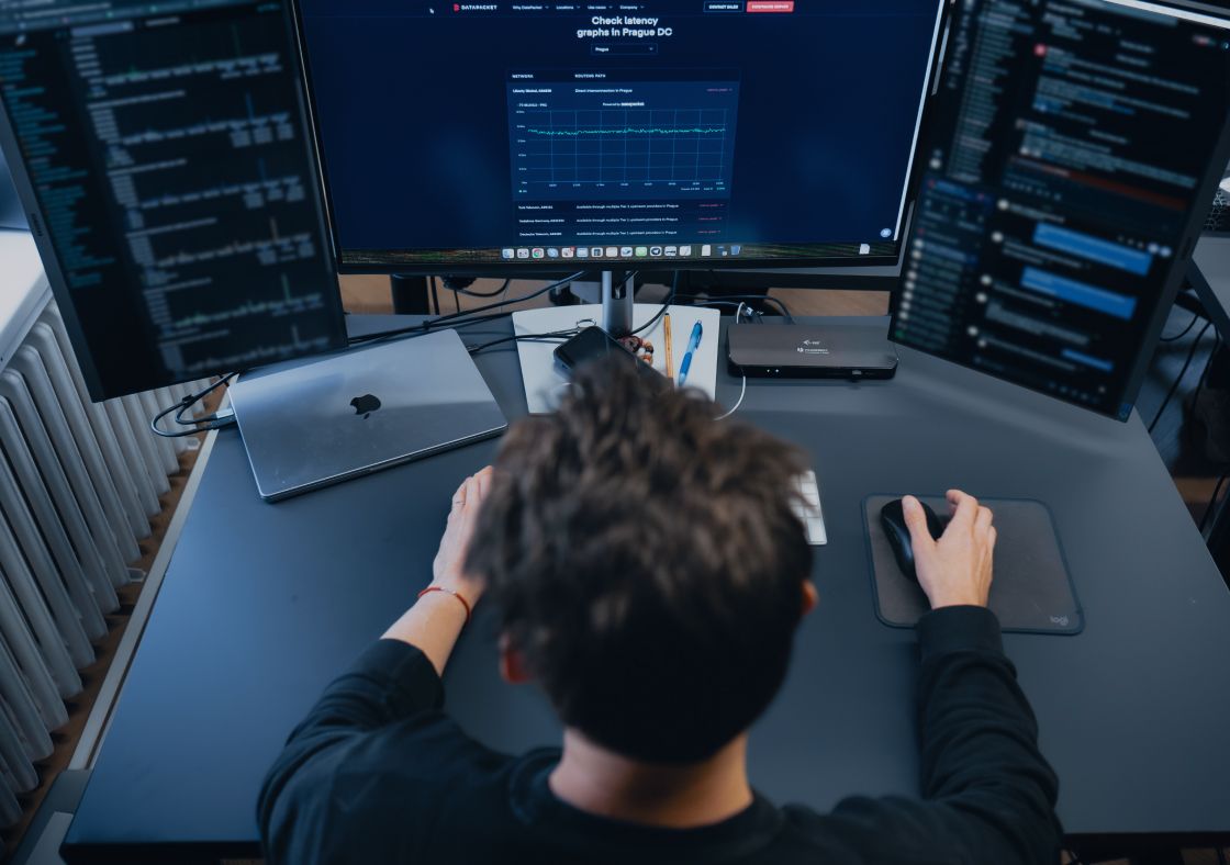 Technician connecting a fiber optic cable in a dense network server rack.